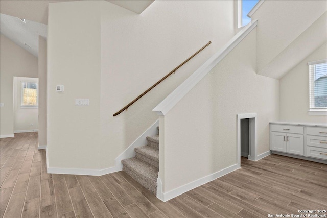 staircase featuring high vaulted ceiling and hardwood / wood-style flooring