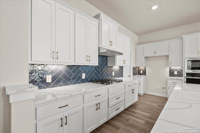 kitchen featuring light stone counters, stainless steel appliances, hardwood / wood-style floors, and white cabinetry