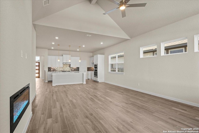 unfurnished living room featuring light hardwood / wood-style floors, ceiling fan, high vaulted ceiling, and beam ceiling