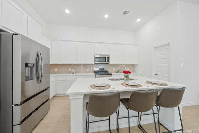 kitchen with stainless steel appliances, a center island with sink, white cabinetry, and sink