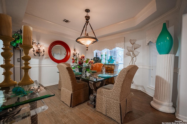 dining area featuring hardwood / wood-style floors, crown molding, and a raised ceiling