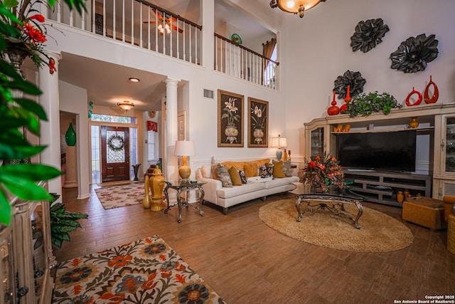 living room with a towering ceiling, hardwood / wood-style floors, and ornate columns