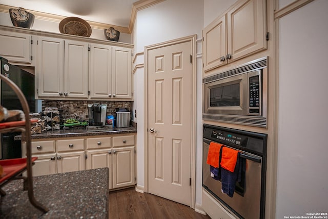 kitchen with crown molding, dark stone counters, dark hardwood / wood-style floors, stainless steel appliances, and backsplash