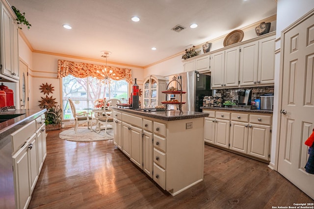 kitchen featuring pendant lighting, hardwood / wood-style flooring, appliances with stainless steel finishes, backsplash, and a kitchen island