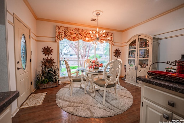 dining area with crown molding, an inviting chandelier, and dark hardwood / wood-style flooring