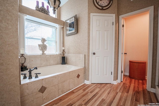 bathroom with hardwood / wood-style floors and a relaxing tiled tub