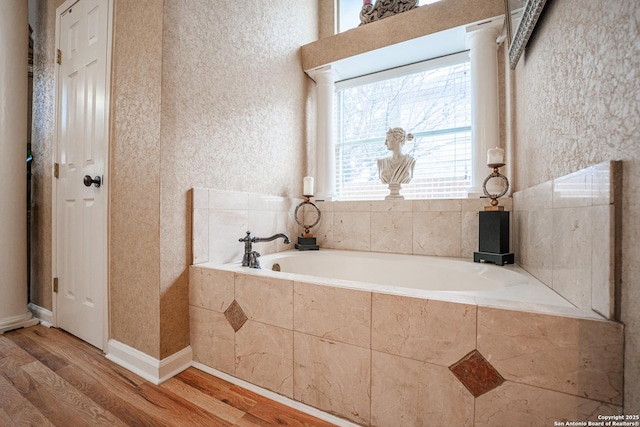 bathroom with a relaxing tiled tub and hardwood / wood-style flooring