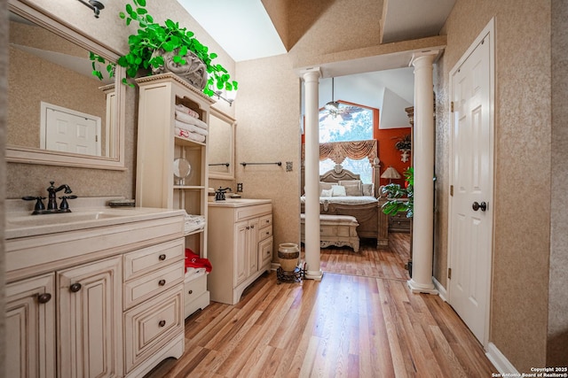 bathroom with decorative columns, vanity, lofted ceiling, and hardwood / wood-style flooring