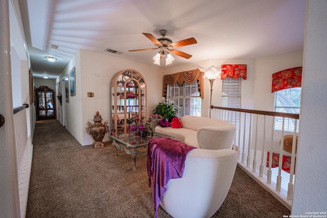 living area with ceiling fan and dark carpet