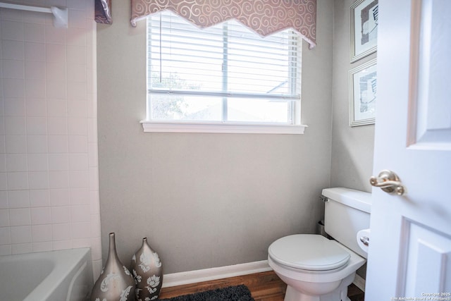 bathroom featuring a tub to relax in, wood-type flooring, and toilet