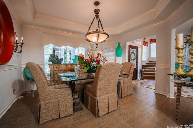 dining area with hardwood / wood-style floors, a tray ceiling, and ornamental molding