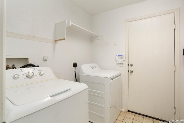 clothes washing area featuring washer and clothes dryer and light tile patterned floors