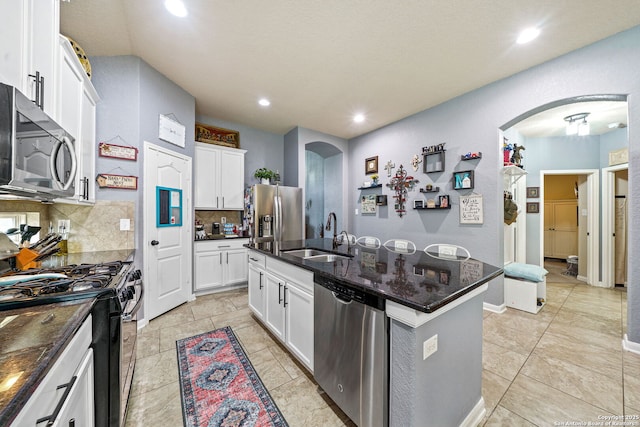 kitchen featuring stainless steel appliances, an island with sink, decorative backsplash, white cabinets, and sink