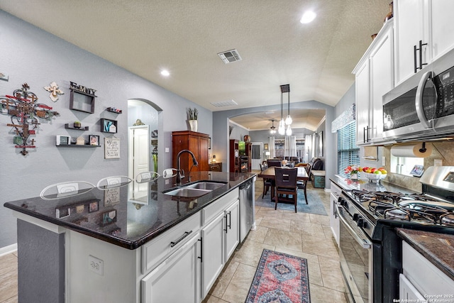 kitchen featuring stainless steel appliances, sink, white cabinets, pendant lighting, and a kitchen island with sink