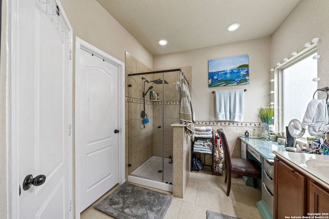 bathroom with tile walls, tile patterned floors, vanity, and a shower with shower door