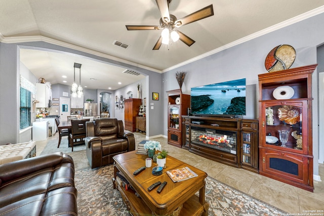 tiled living room with ceiling fan with notable chandelier, ornamental molding, and vaulted ceiling