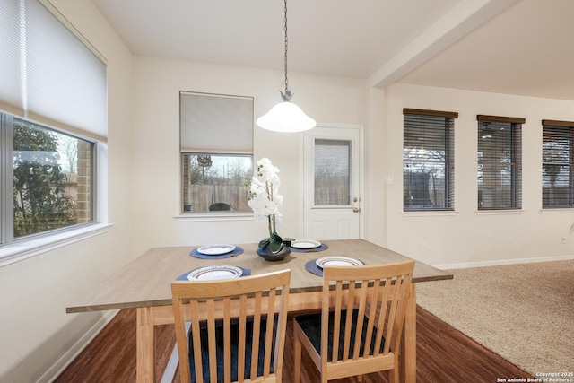 carpeted dining area with beam ceiling