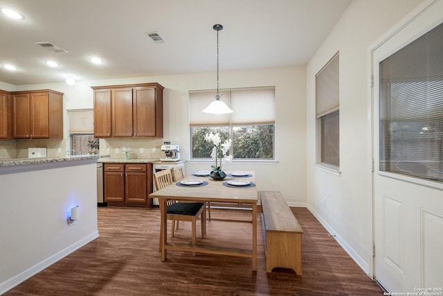 kitchen with tasteful backsplash, stainless steel dishwasher, dark hardwood / wood-style floors, pendant lighting, and light stone countertops