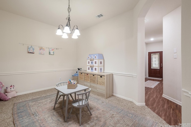 carpeted dining area with a chandelier