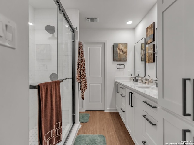 bathroom featuring wood-type flooring, an enclosed shower, and vanity