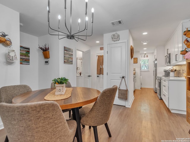 dining space featuring light wood-type flooring and an inviting chandelier