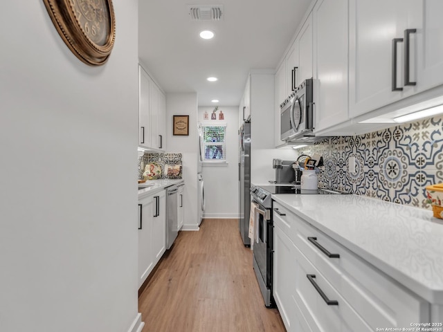 kitchen with light wood-type flooring, stainless steel appliances, and white cabinetry