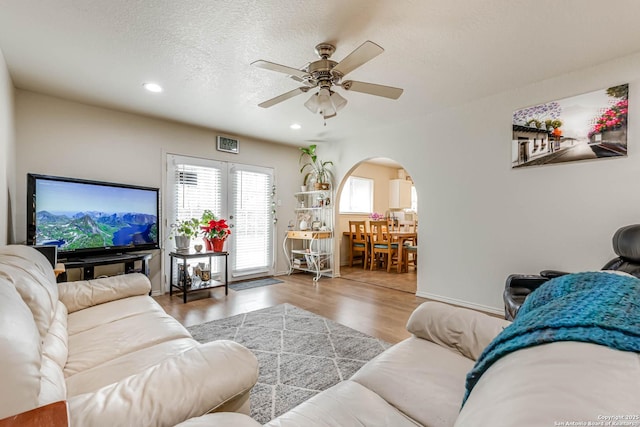 living room with a textured ceiling, ceiling fan, and hardwood / wood-style flooring