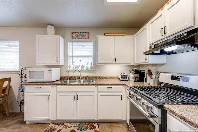 kitchen featuring light stone countertops, stainless steel gas range, light tile patterned floors, white cabinets, and sink