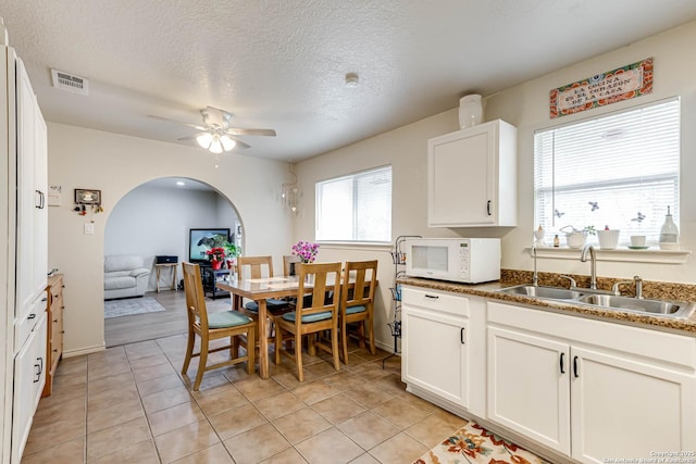 tiled dining space with sink, a textured ceiling, and ceiling fan