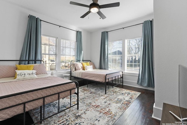 bedroom featuring ceiling fan, dark wood-type flooring, and multiple windows