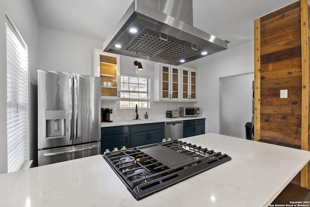 kitchen featuring sink, light stone counters, island exhaust hood, and appliances with stainless steel finishes