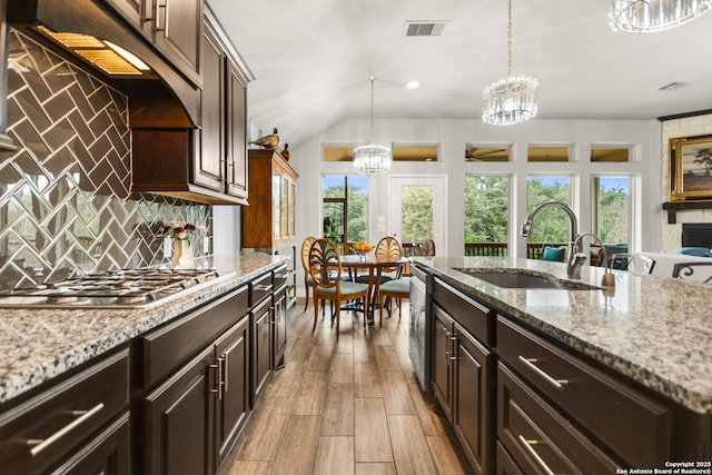 kitchen with sink, hanging light fixtures, dark brown cabinets, and decorative backsplash