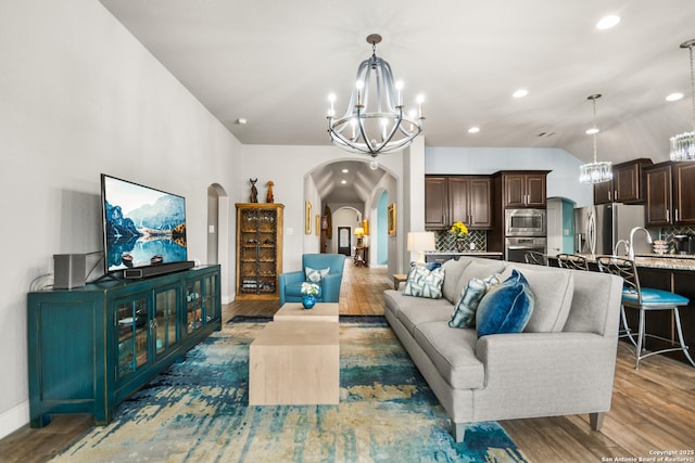 living room featuring an inviting chandelier, vaulted ceiling, and dark hardwood / wood-style floors