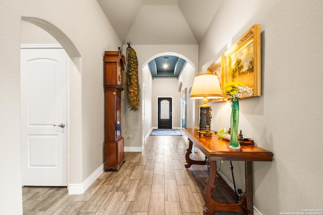 hallway with vaulted ceiling and light hardwood / wood-style floors