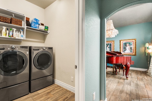 clothes washing area with a chandelier, light hardwood / wood-style floors, and washer and clothes dryer