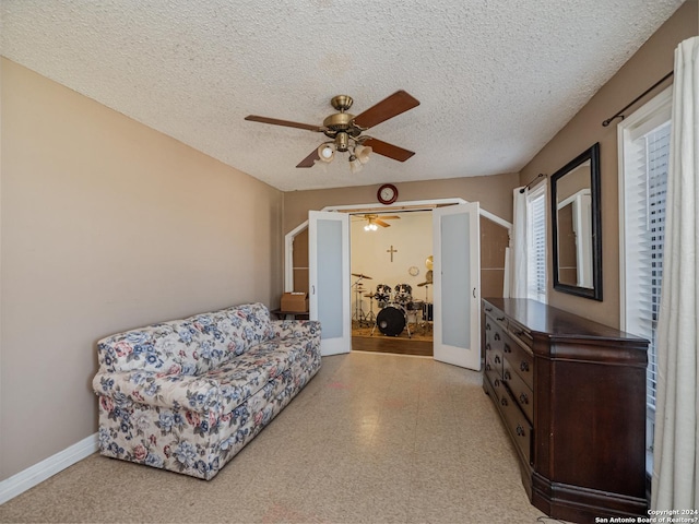 living area with a textured ceiling and ceiling fan