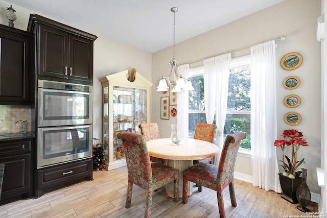 dining room featuring light wood-type flooring, a notable chandelier, and plenty of natural light