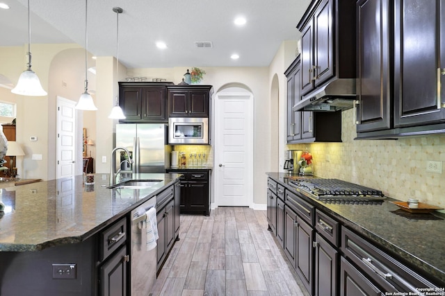 kitchen with decorative light fixtures, stainless steel appliances, dark stone countertops, and sink