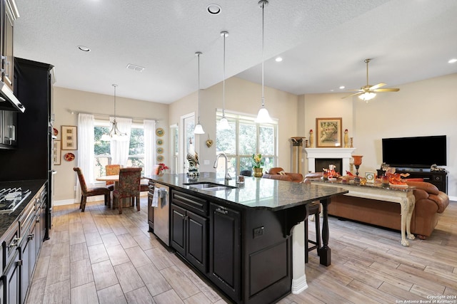 kitchen with a kitchen breakfast bar, hanging light fixtures, an island with sink, ceiling fan, and sink