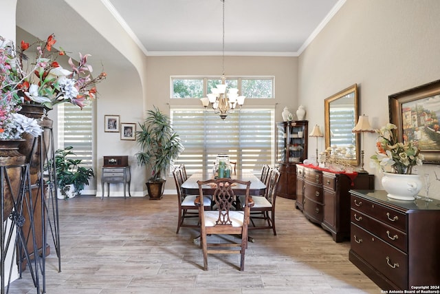 dining area featuring ornamental molding, light wood-type flooring, and a notable chandelier