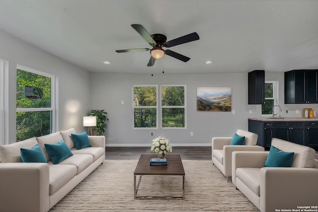 living room featuring ceiling fan, light hardwood / wood-style floors, and sink