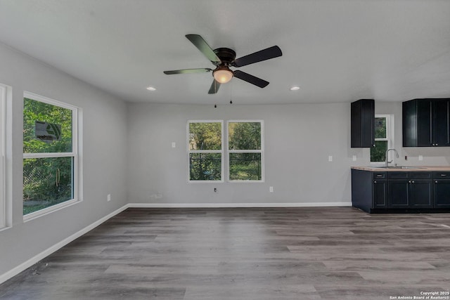 unfurnished living room with light hardwood / wood-style floors, sink, and plenty of natural light