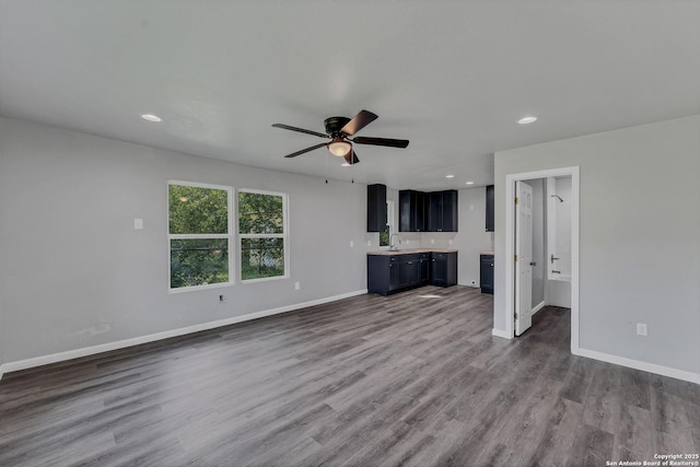 unfurnished living room with sink, hardwood / wood-style floors, and ceiling fan