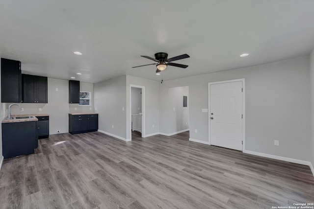 unfurnished living room with ceiling fan, light hardwood / wood-style floors, and sink