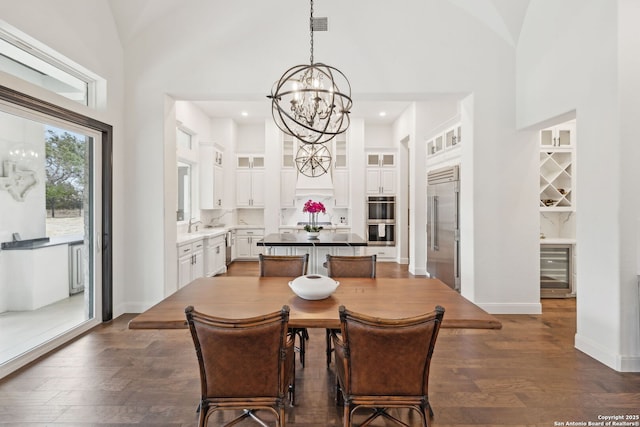 dining area featuring high vaulted ceiling, an inviting chandelier, wine cooler, and dark hardwood / wood-style floors