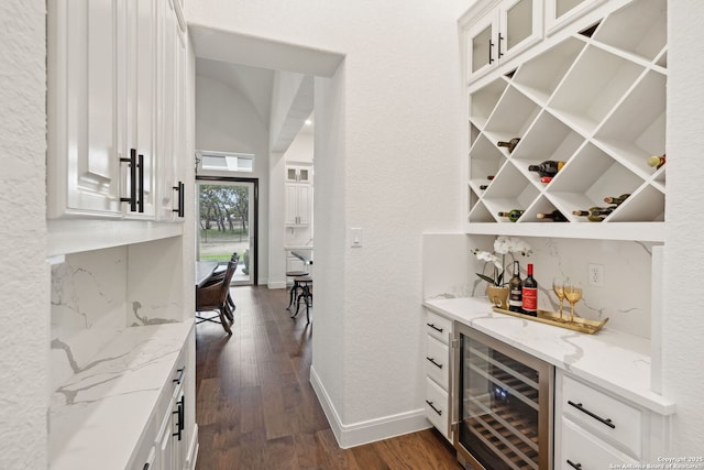 bar with dark hardwood / wood-style flooring, white cabinets, wine cooler, and light stone countertops