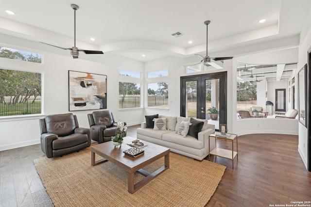 living room with dark wood-type flooring, a raised ceiling, french doors, and ceiling fan