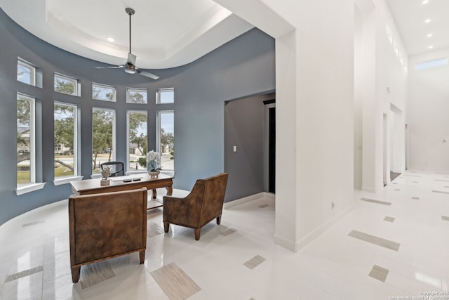 tiled office with a high ceiling, a raised ceiling, and ceiling fan