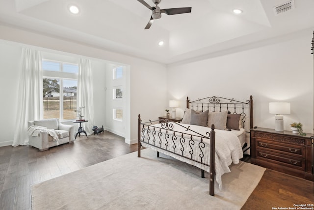 bedroom featuring dark wood-type flooring, a raised ceiling, and ceiling fan