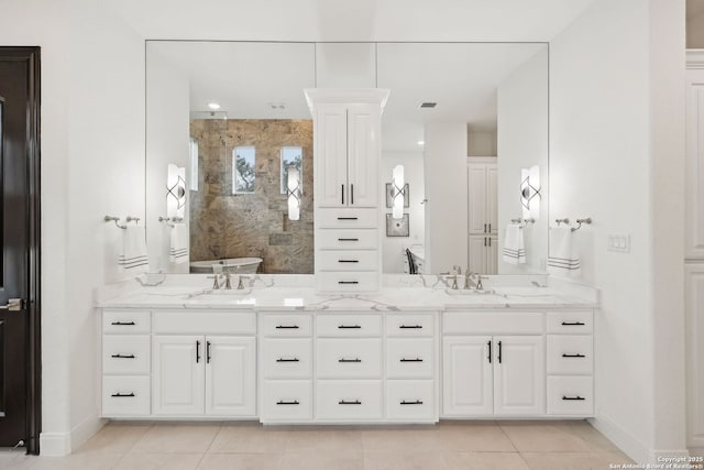 bathroom with tile patterned flooring, tiled shower, and vanity